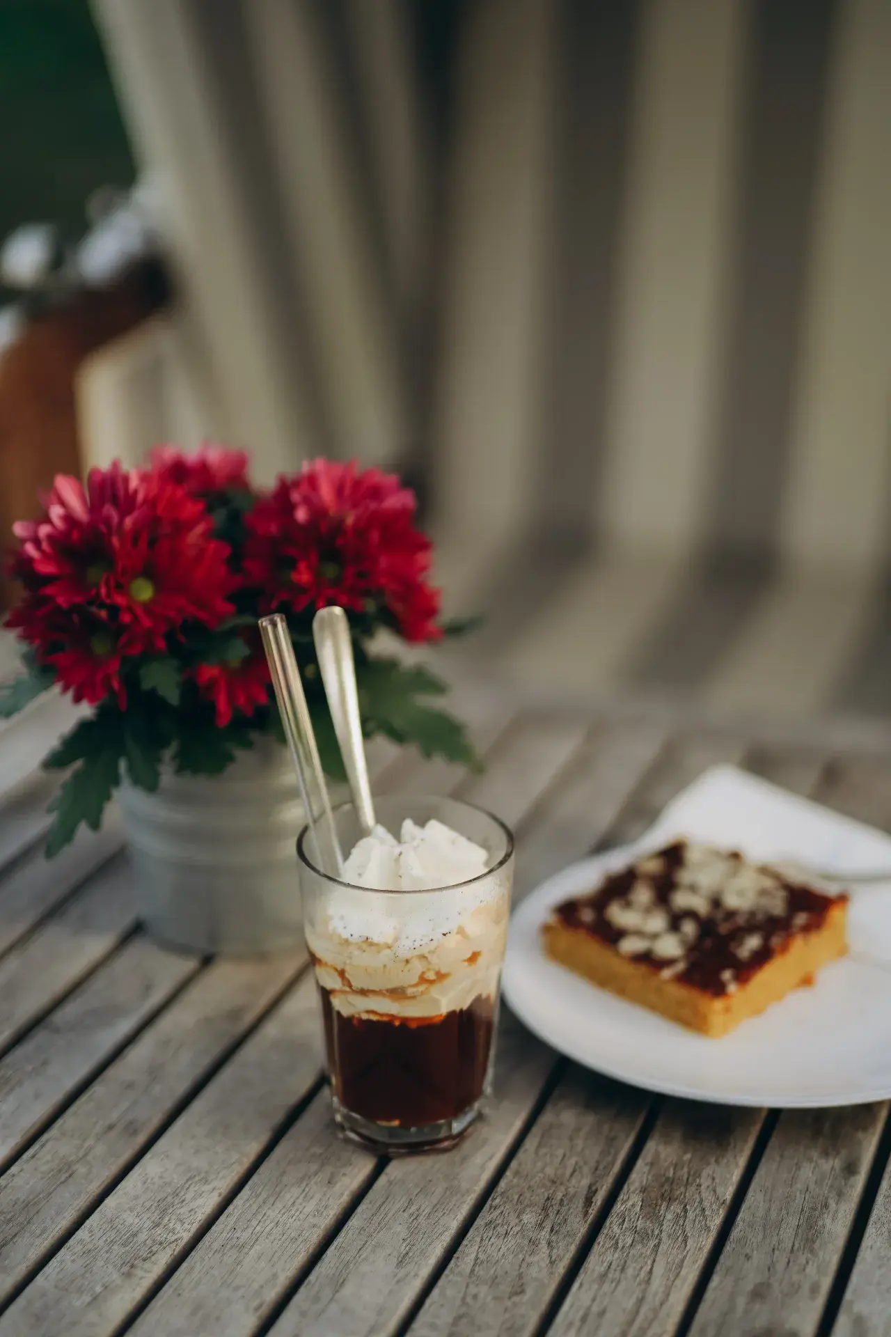 Eiskaffee im Glas mit roten Blumen und einem Stück Kuchen