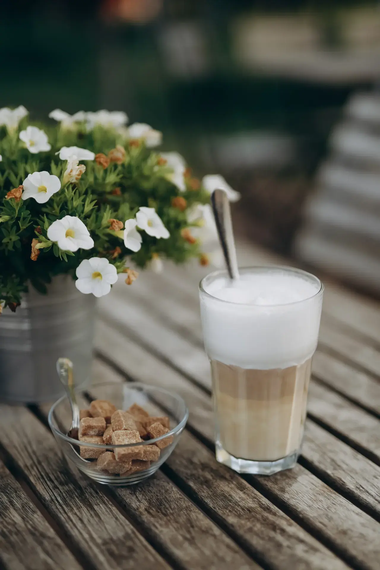 Latte Macchiato mit weißen Blumen und braunem Zucker