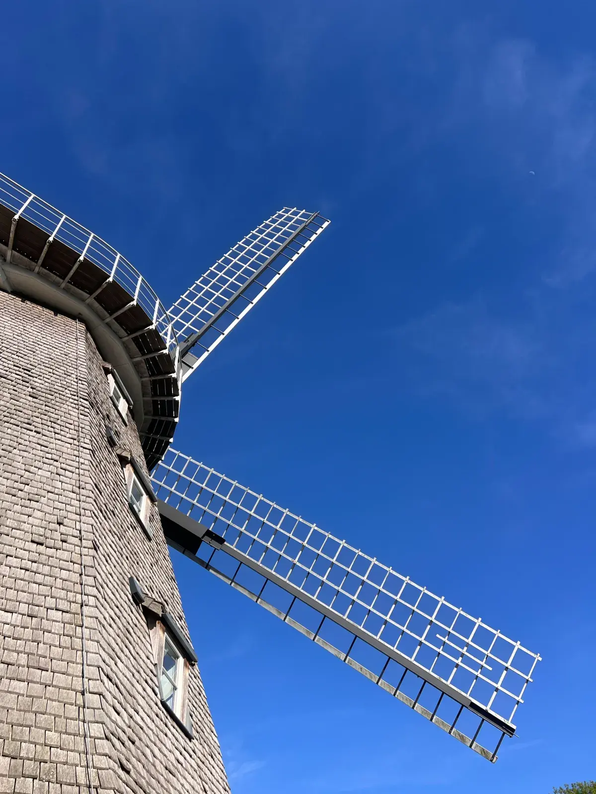 Aufblick auf Schindelturm und Flügel der Mühle vor tiefblauem Himmel