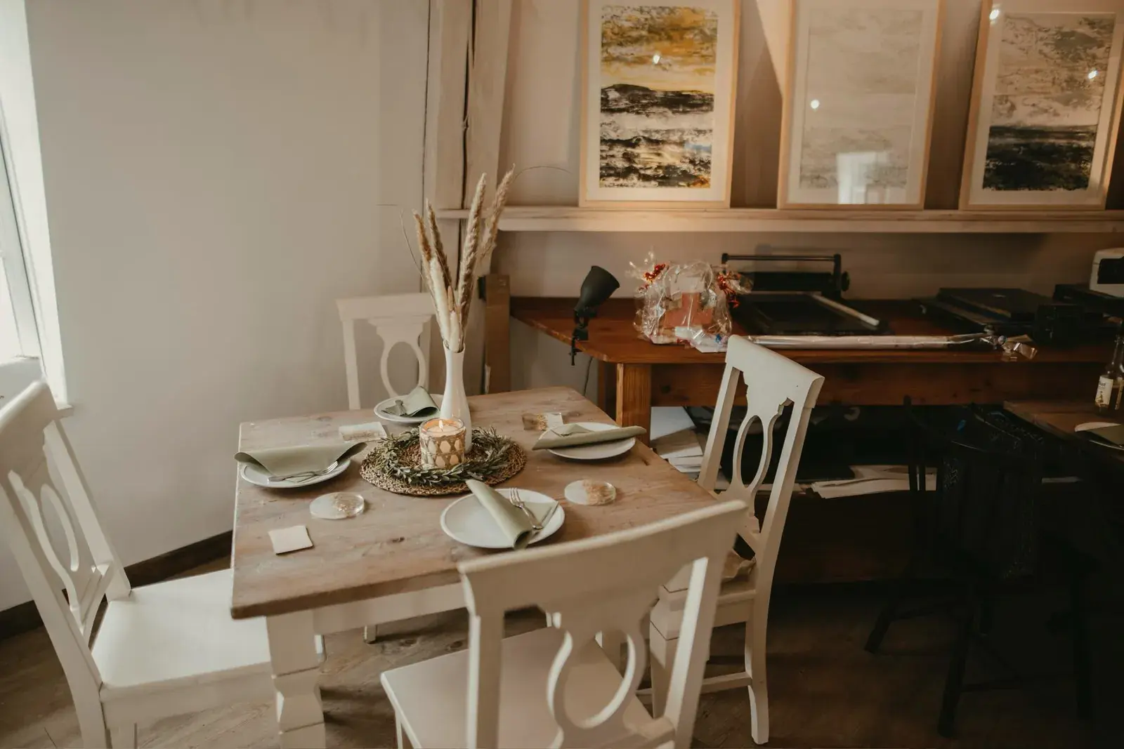 Gedeckter Tisch im Café der Mühle, dahinter Kunstwerke und eine historische Nähmaschine