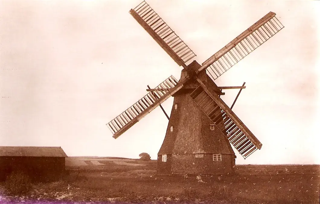 Historische Sepia-Aufnahme der alten Windmühle mit vollen Flügeln und einem Schuppen