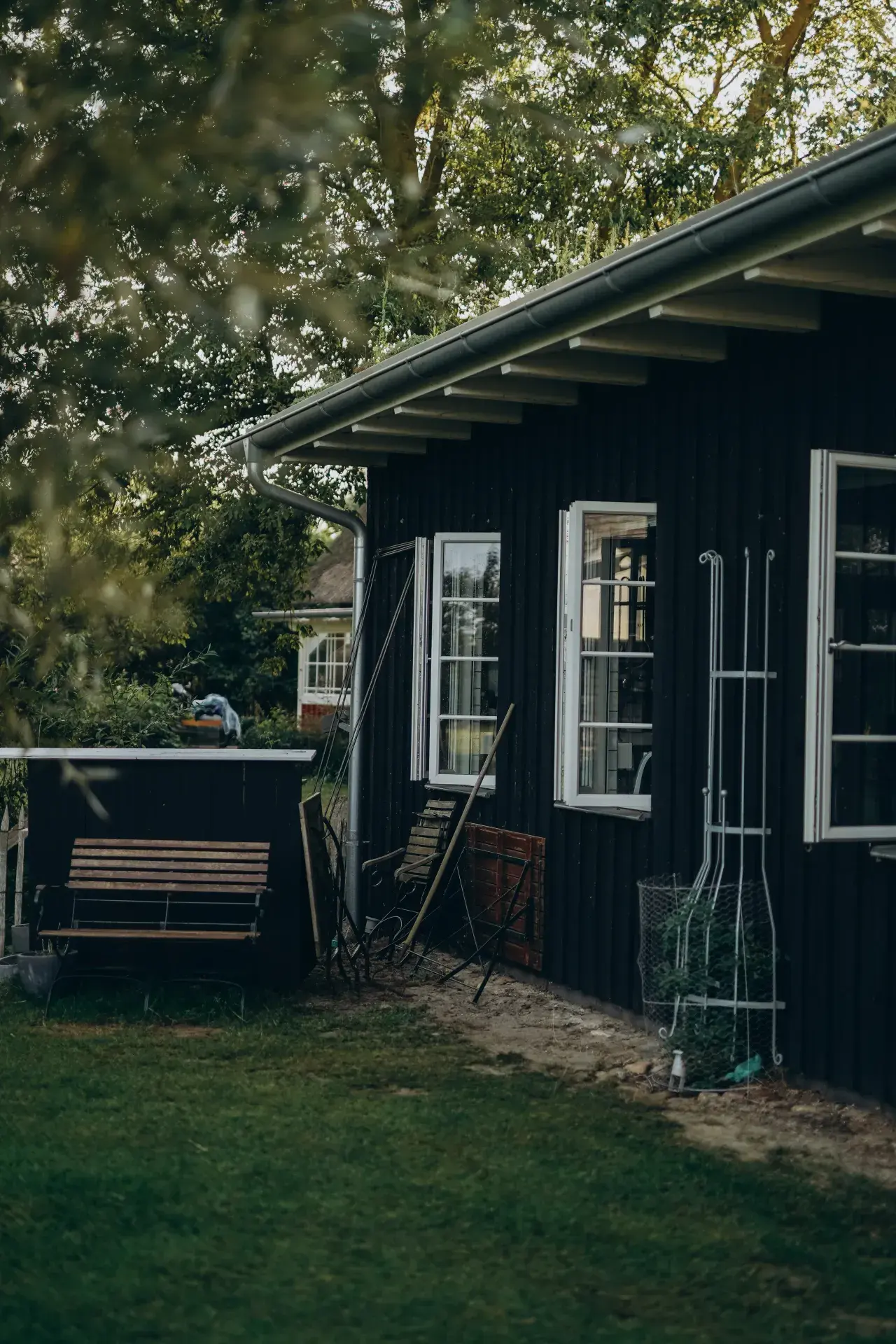 Das schwarze Café-Gebäude der Mühle Ahrenshoop mit Hollywoodschaukel im Garten