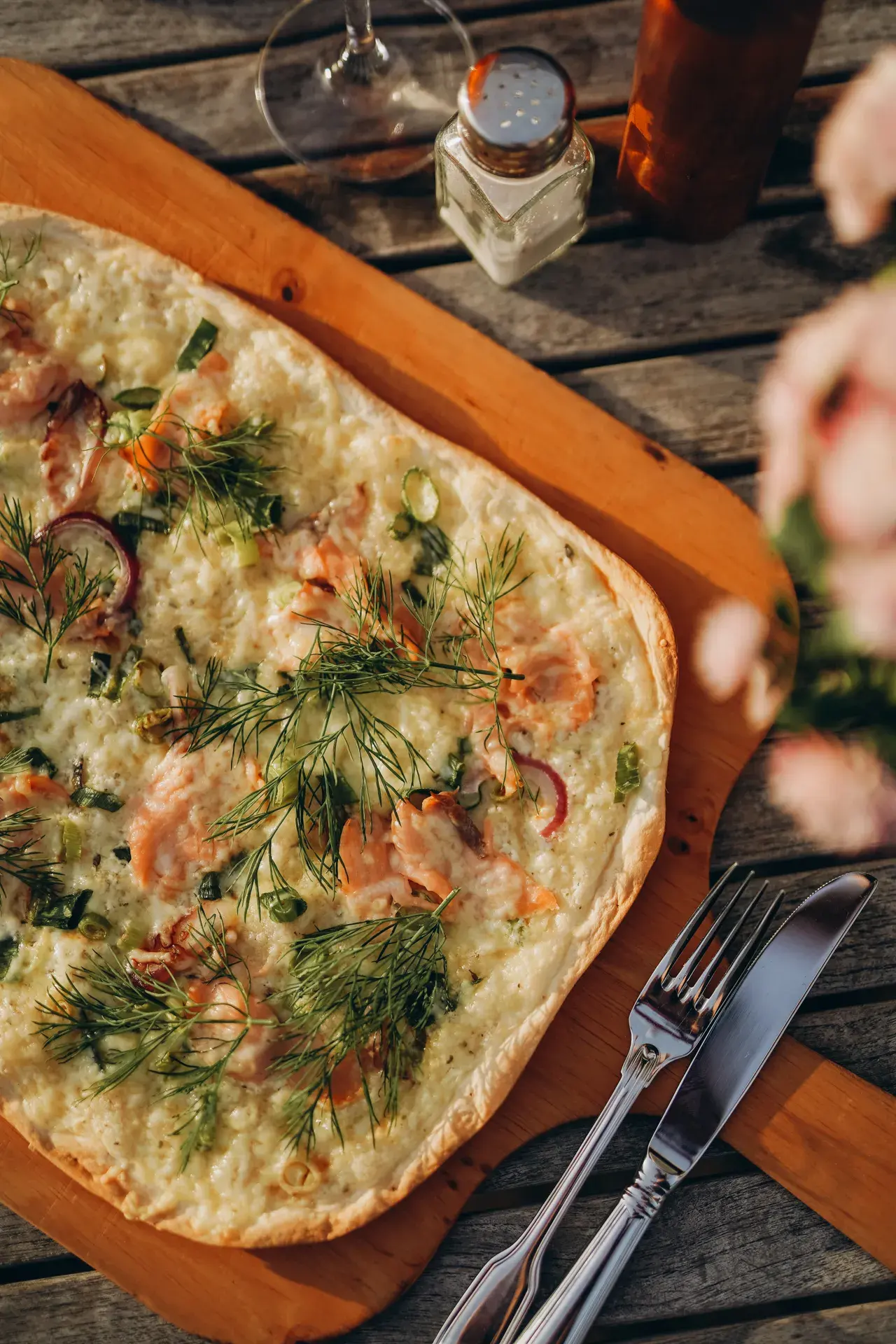 Lachs-Flammkuchen mit Dill und roten Zwiebeln auf einem Holzbrett
